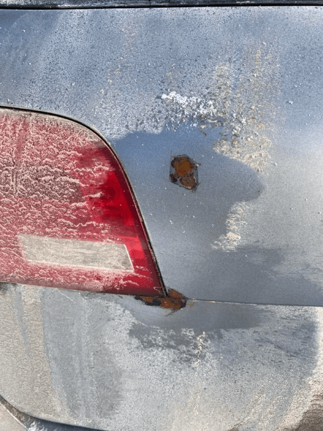 car buried in wet leaves with rust spots highlighted