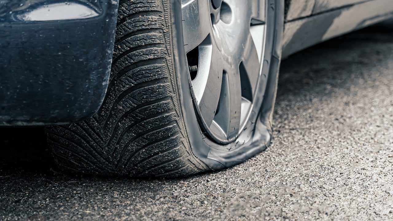 photo of a car with a flat tire and a frustrated driver.