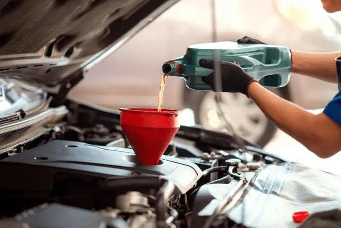 photo of funnel in oil fill hole with a hand pouring oil photo of funnel in oil fill hole with a hand pouring oil